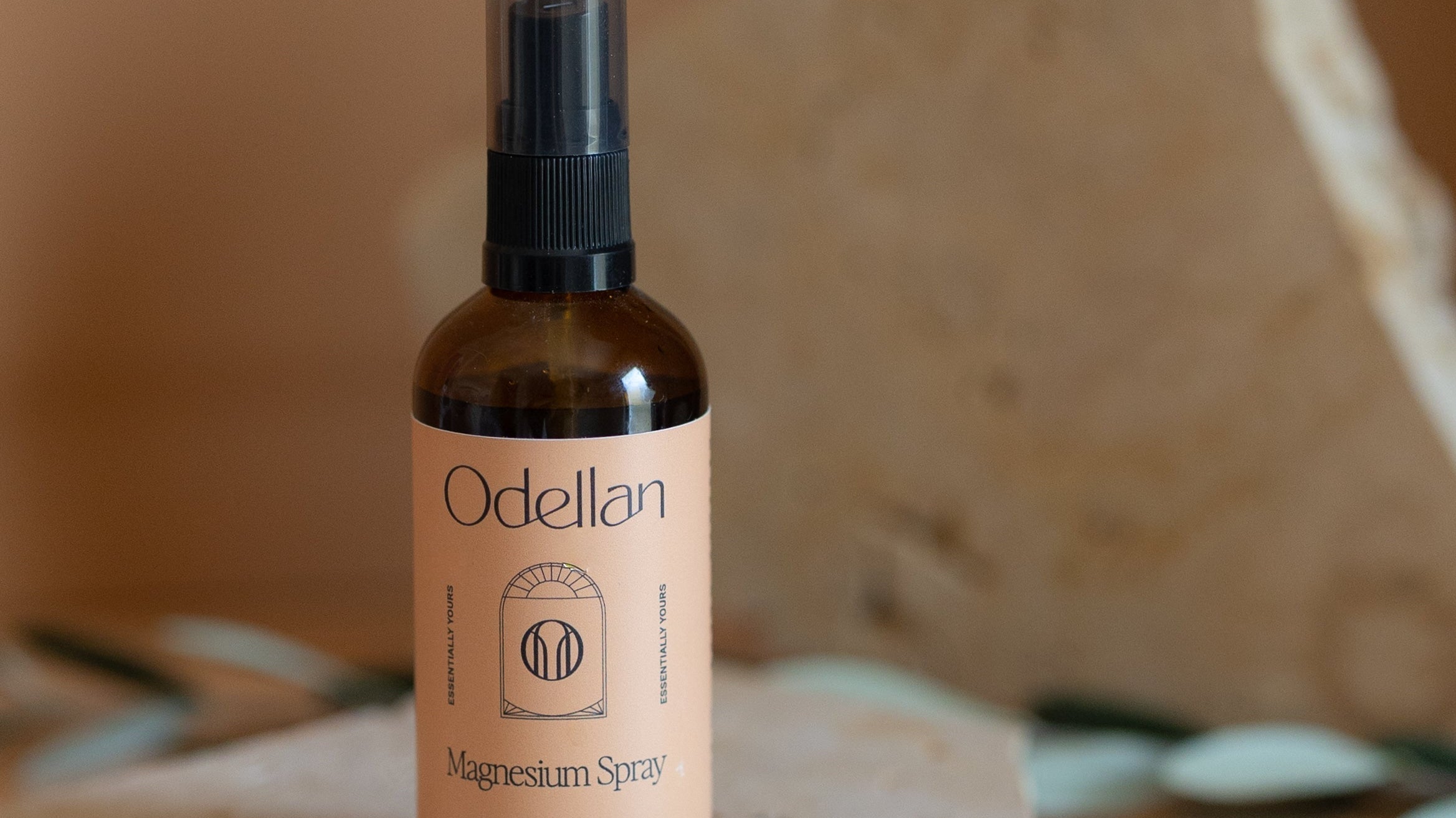 Odellan's Magnesium Oil spray travel bottle on a stone