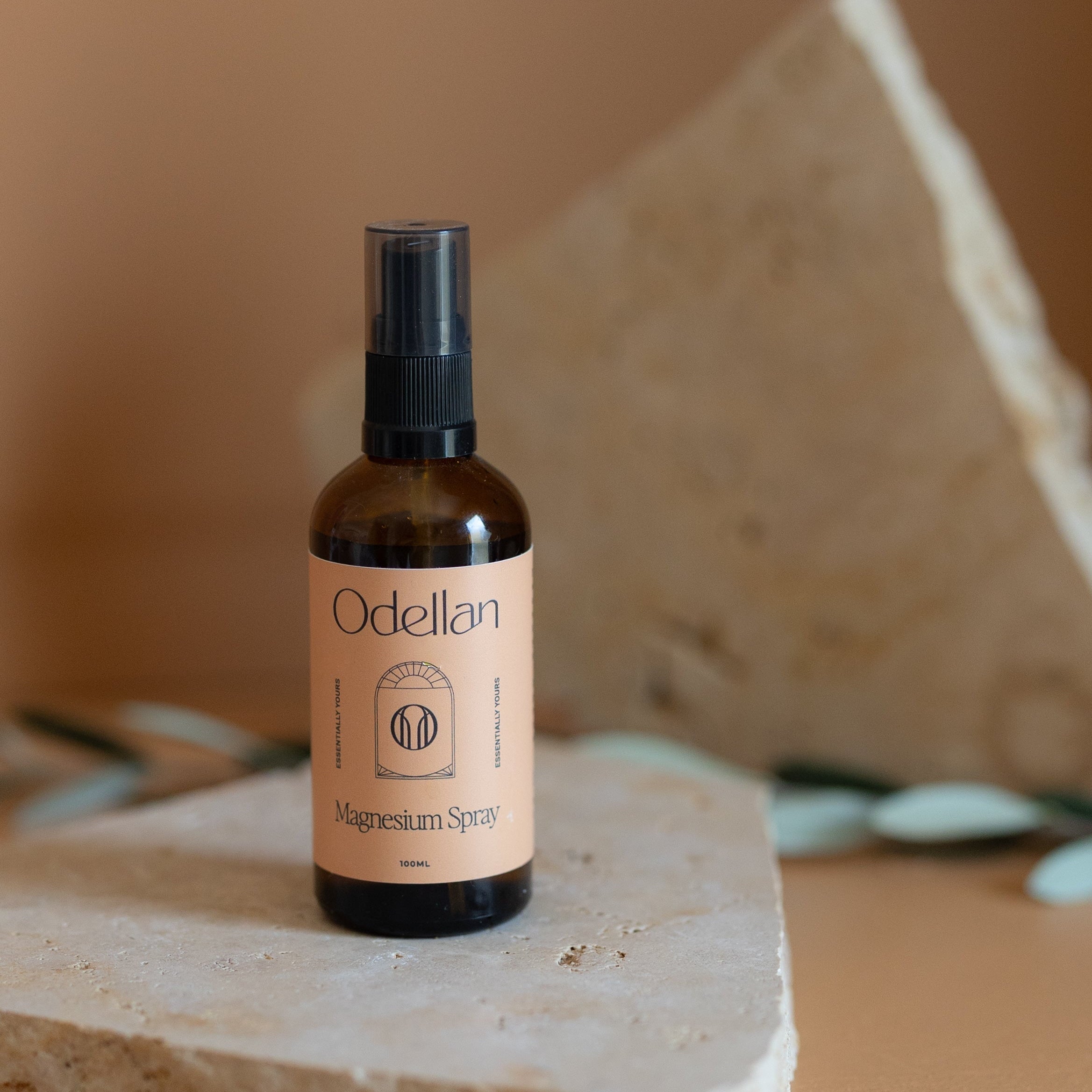 Odellan's Magnesium Oil spray travel bottle on a stone